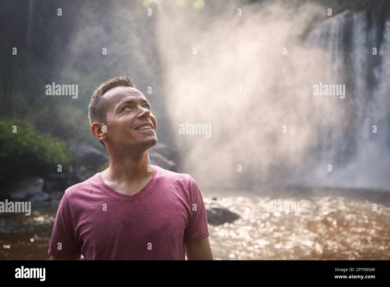 Porträt des Reisenden vor dem Hochwasserfall. Glücklicher Mann in tropischer Natur in Kambodscha. Stockfoto