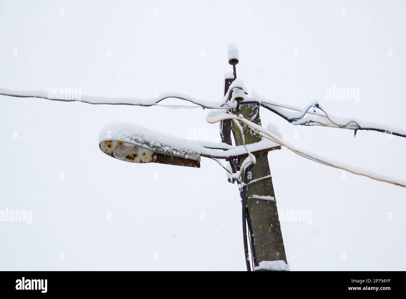 Viel Schnee in der Reihe von elektrischen Kabeln und Lampen Stockfoto