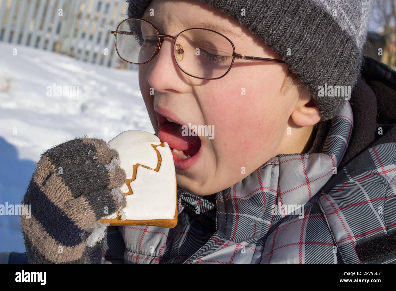 Der Junge isst Kekse im Winter auf der Straße Stockfoto