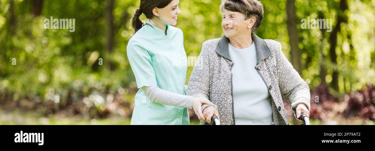Ältere behinderte Frau mit Pflegekraft im Garten des Pflegeheims Stockfoto