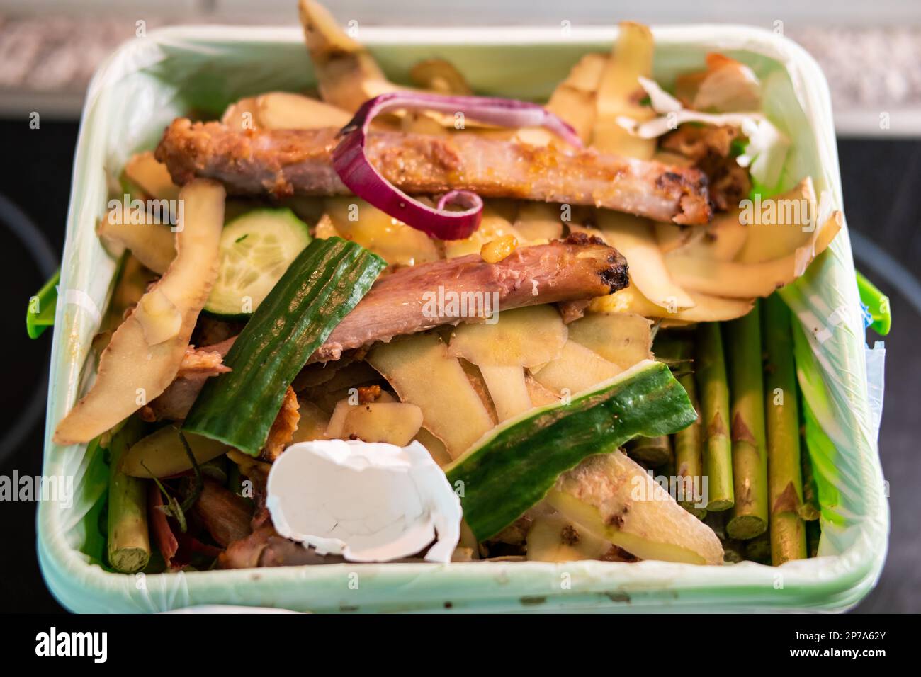 Lebensmittelabfallbehälter voller verdorbenem Gemüsefleisch und Knochen, bereit für Kompost-Recycling Nahaufnahme Draufsicht. Stockfoto
