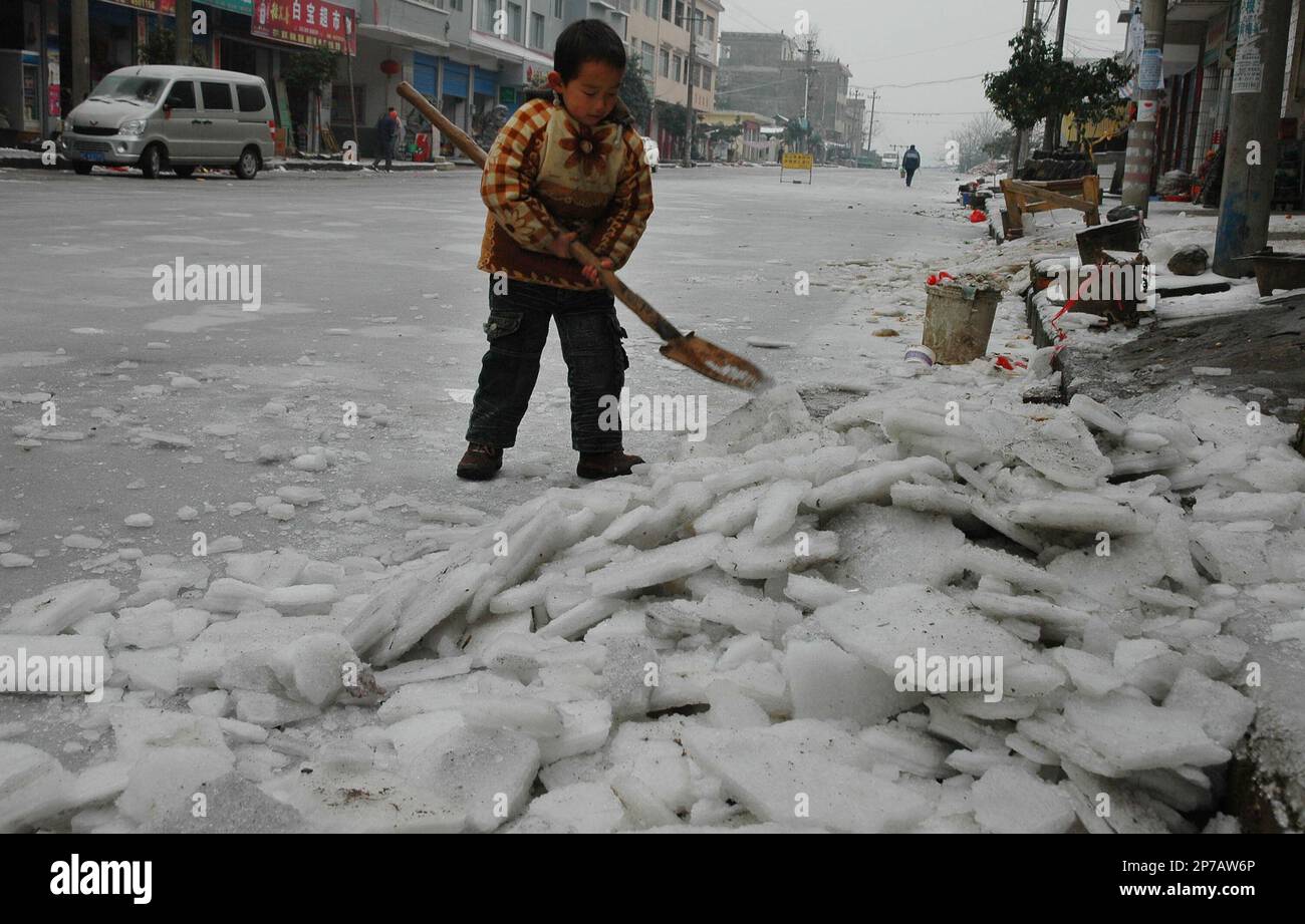 A child shovels ice and snow on a street in Baibao country in Guilin in southwest China's Guangxi Zhuang Autonomous Region on Tuesday, Jan. 4, 2011. Many parts of China are embracing for more heavy snow and below-freezing temperatures.(Photo By Tang Mengxian/Color China Photo/AP Images) Stockfoto