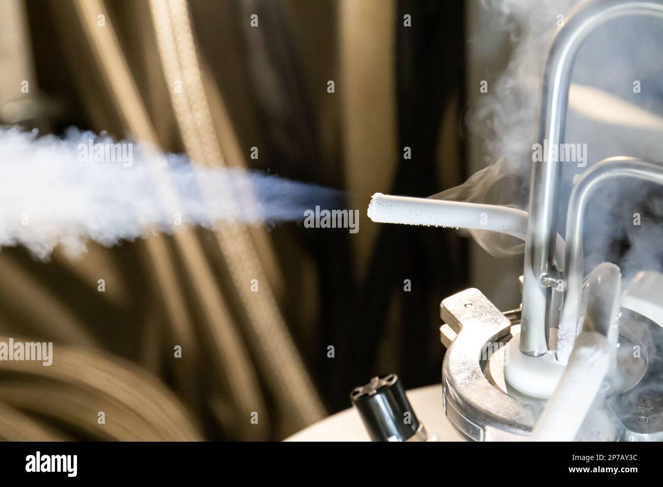 Flüssiges Stickstoffgas, das aus dem unter Druck stehenden Tank austritt, Thermogummischlauch, der mit Metallrohren und roten Handventilen verbunden ist. Stockfoto
