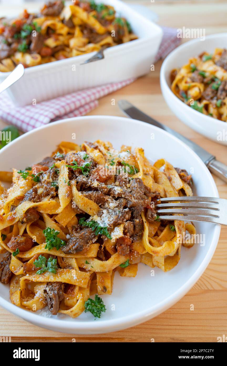 Pasta mit Rindfleisch und Gemüse auf Tellern auf dem Küchentisch Stockfoto