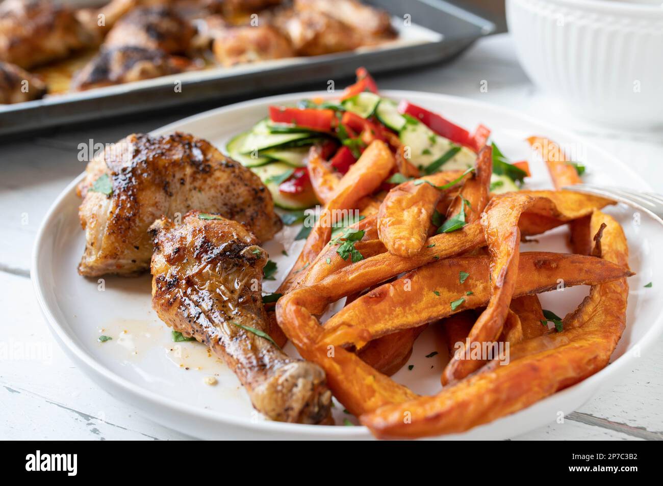 Gegrilltes Hähnchen mit Süßkartoffeln und mediterranem Salat auf einem Teller Stockfoto