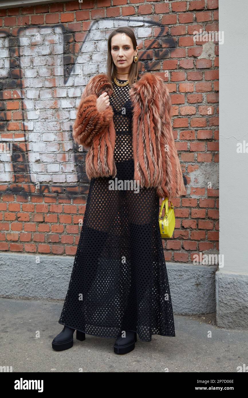 MAILAND, ITALIEN - 22. FEBRUAR 2023: Frau mit brauner Pelzjacke und schwarzem Piercierced-Kleid vor der Fendi-Modenschau, Mailand Fashion Week Street Style Stockfoto