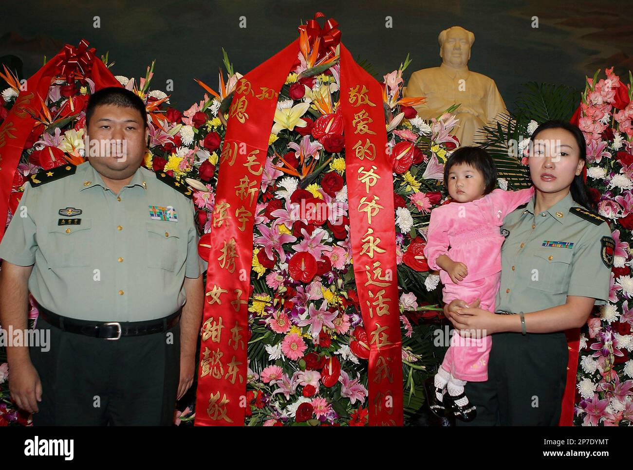 Mao Xinyu, left, the grandson of late Chinese communist leader Mao Zedong, his wife Liu Bin, right, and their two-year-old daughter Mao Tianyi pose for photos near wreaths in front of a Mao Zedong sculpture at the Chairman Mao Memorial Hall in Beijing, China, on the 34th anniversary of Mao Zedong's death, Thursday, Sept. 9, 2010. Mao Xinyu has recently been promoted to become China's youngest major general. (AP Photo) ** CHINA OUT ** Stockfoto