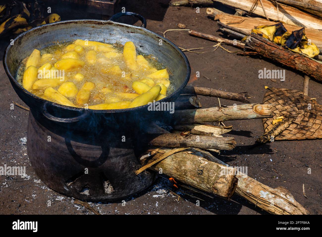 Ein köstlicher Snack ist das Frittieren von frischer Planane in einer Metallpfanne auf einem offenen Holzdraht an einem Verkaufsstand am Straßenrand in benin westafrika Stockfoto