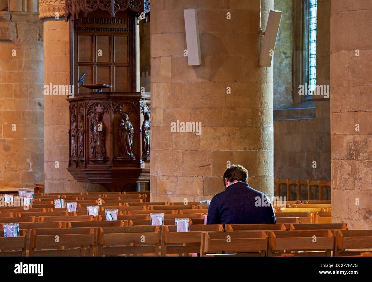 Ein Mann sitzt auf der Bank, im Inneren von Southwell Minster, Southwell, Nottinghamshire, England, Großbritannien Stockfoto