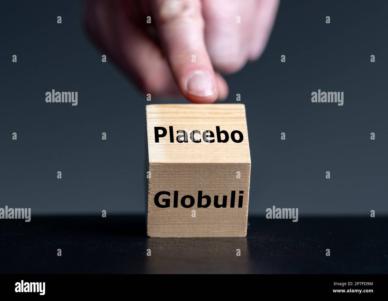Symbol, dass die homöopathische Medizin nur einen Placebo-Effekt hat. Die Hand dreht den Würfel um und ändert das deutsche Wort „Glubuli“ (Globule) in „Placebo“. Stockfoto