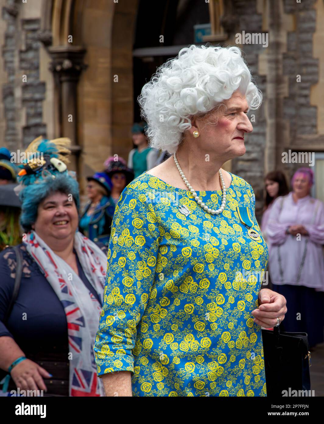 Ein Mann, verkleidet wie eine Frau, trägt ein Chinzkleid und eine weiße Perücke. Stockfoto