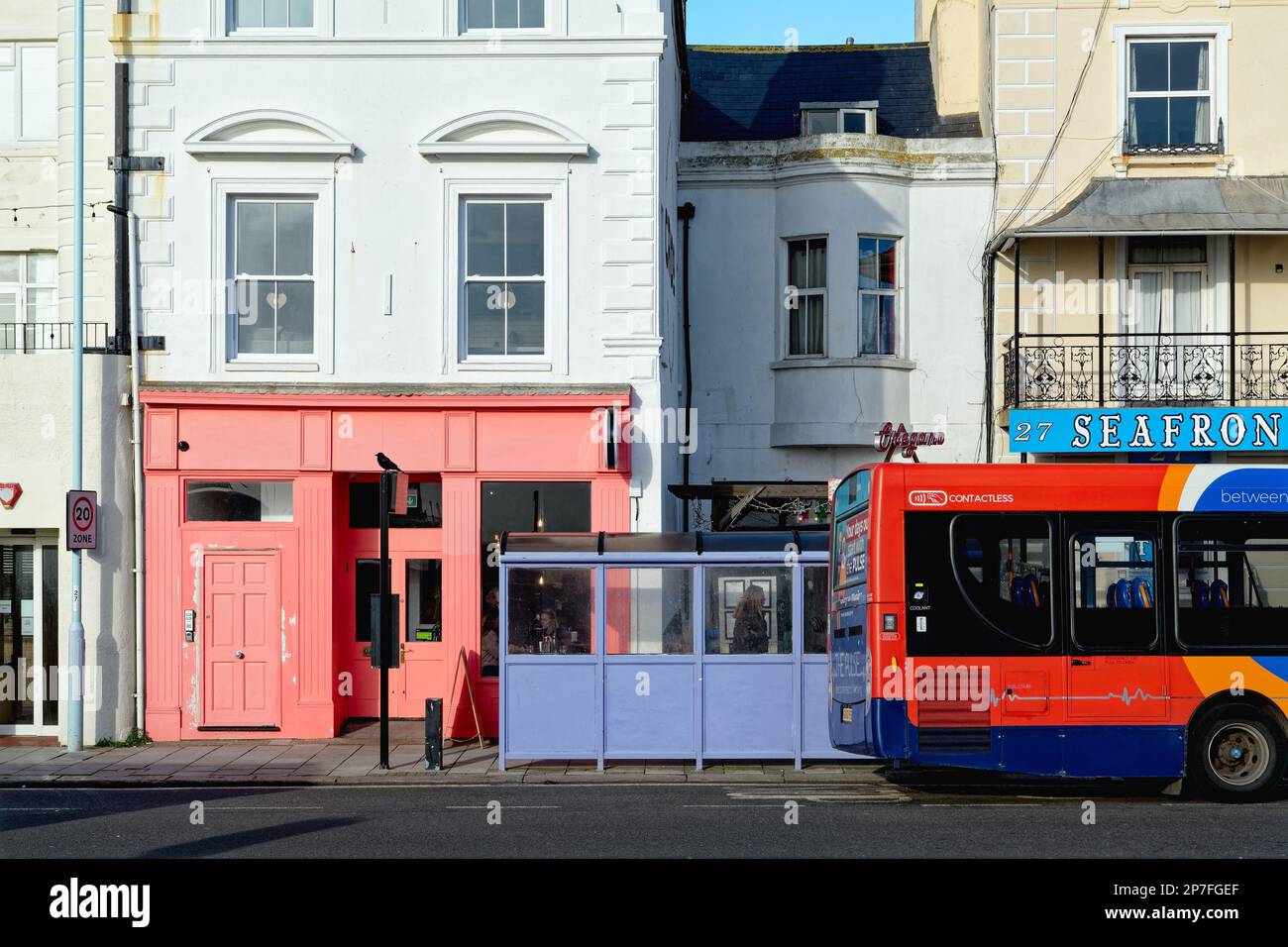 Eine urbane Landschaft an der Küste von Worthing, die ein halbabstraktes Design aus einem roten Bus und einem gemalten quadratischen Gebäude, West Sussex England, schafft Stockfoto