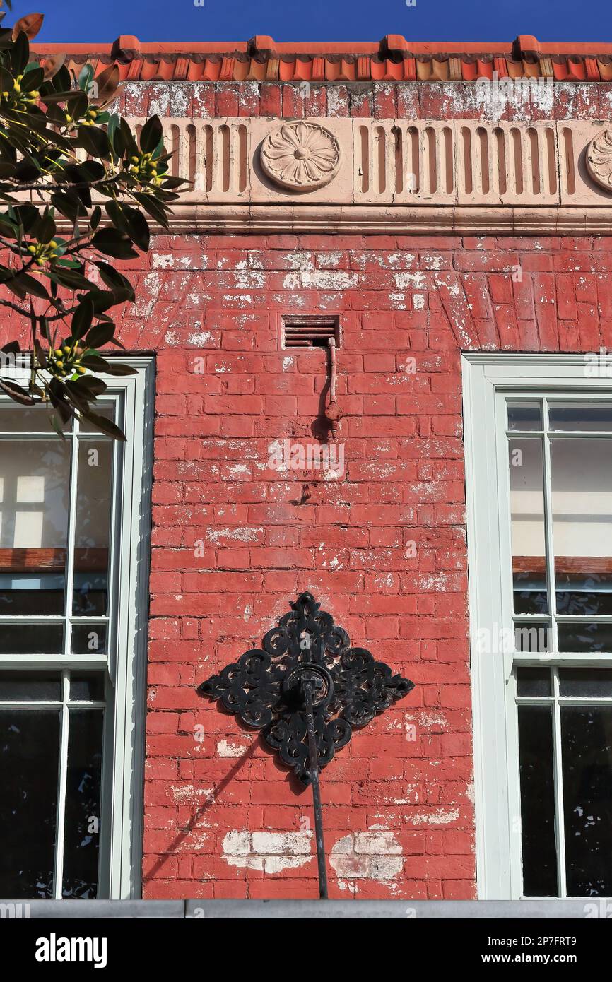 Rote Backsteinfassade aus den 532 Jahren mit gewellten Frieze-Blumenmedaillons, schmiedeeiserner Plattendekoration, AD1928 erbautes Gebäude im Vorort Corso-Manly. Sydney-AUS Stockfoto