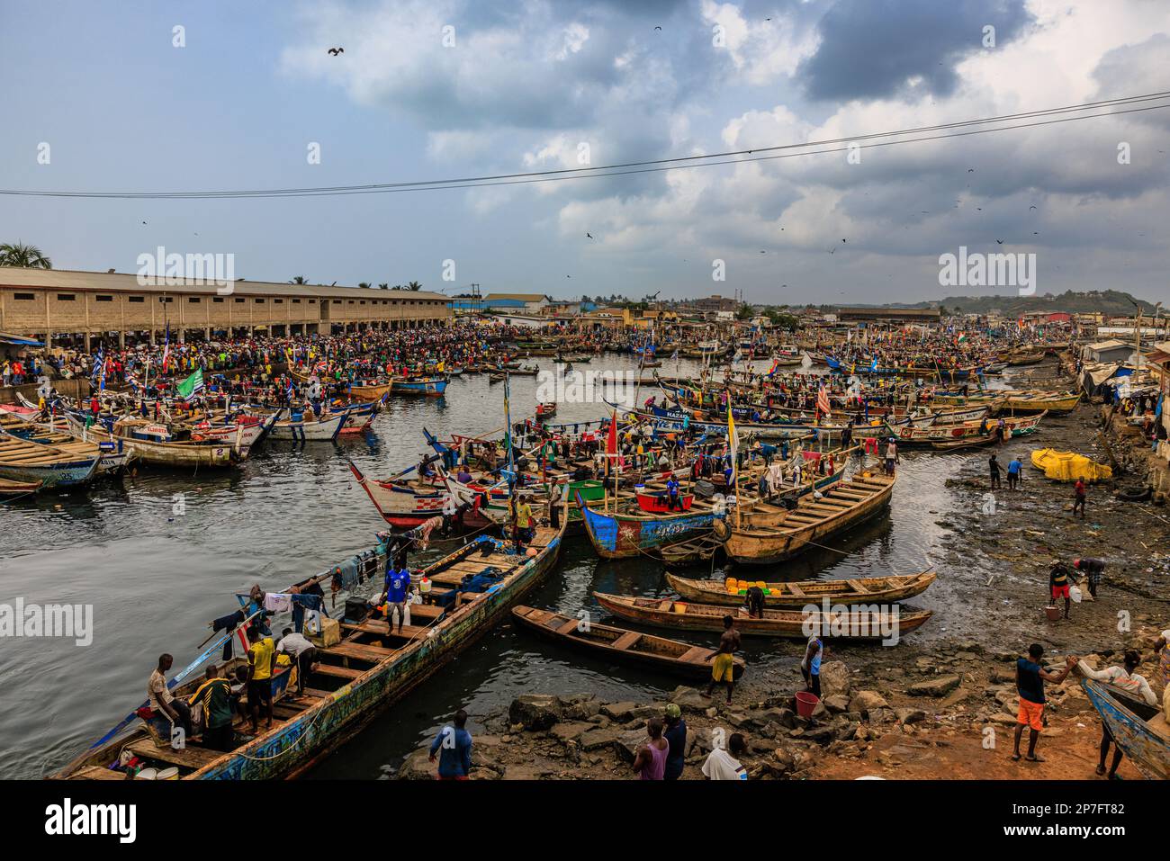 Blick von oben auf den belebten Fischereihafen und den Markt von elmina ghana Hunderte von Arbeitern, die traditionelle Holzboote auf den Markt laden Stockfoto