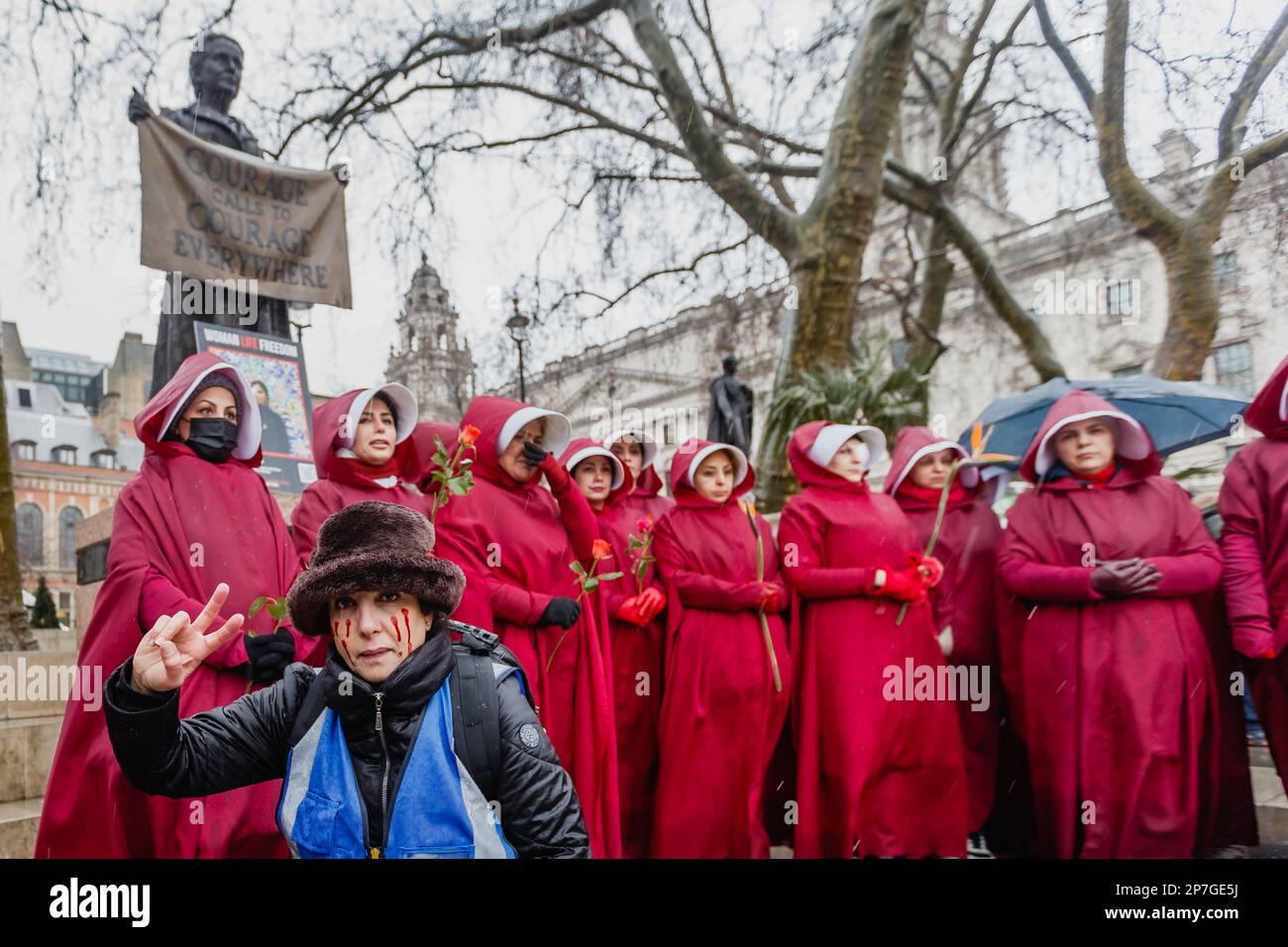 Britisch-iranische Demonstranten, die wie Figuren aus dem Magazin des Magazins am Internationalen Frauentag 2023 gekleidet sind, stehen unter einem Suffragette. Stockfoto