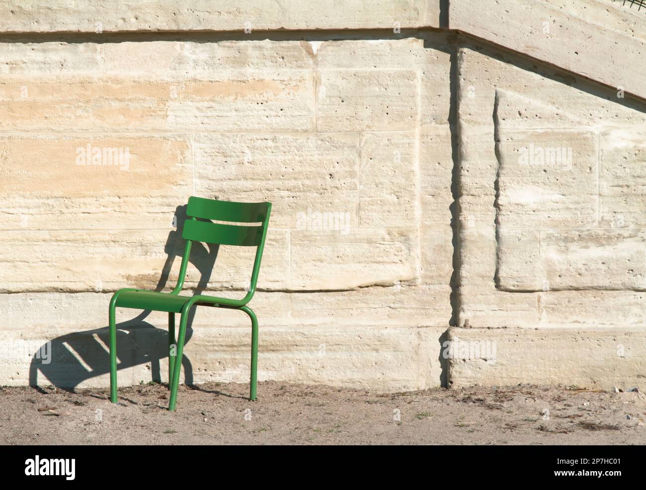 Ein leerer grüner Stuhl gegen Eine Steinmauer in den Jardin Tuilerien, Paris, Frankreich Stockfoto