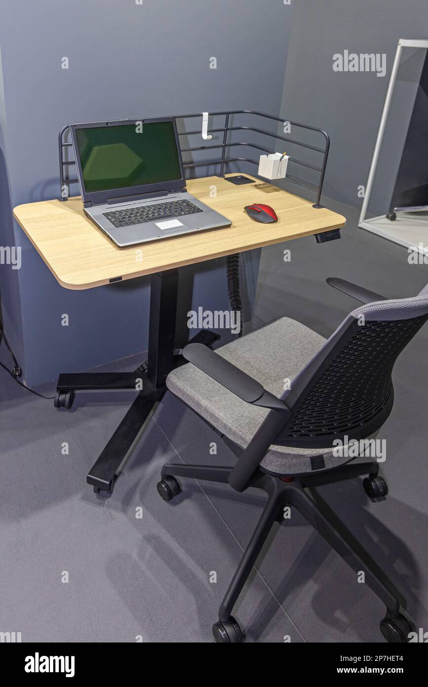 Laptop-Computer und Maus an kleinem mobilen Schreibtisch mit Rädern am Arbeitsplatz öffnen Stockfoto