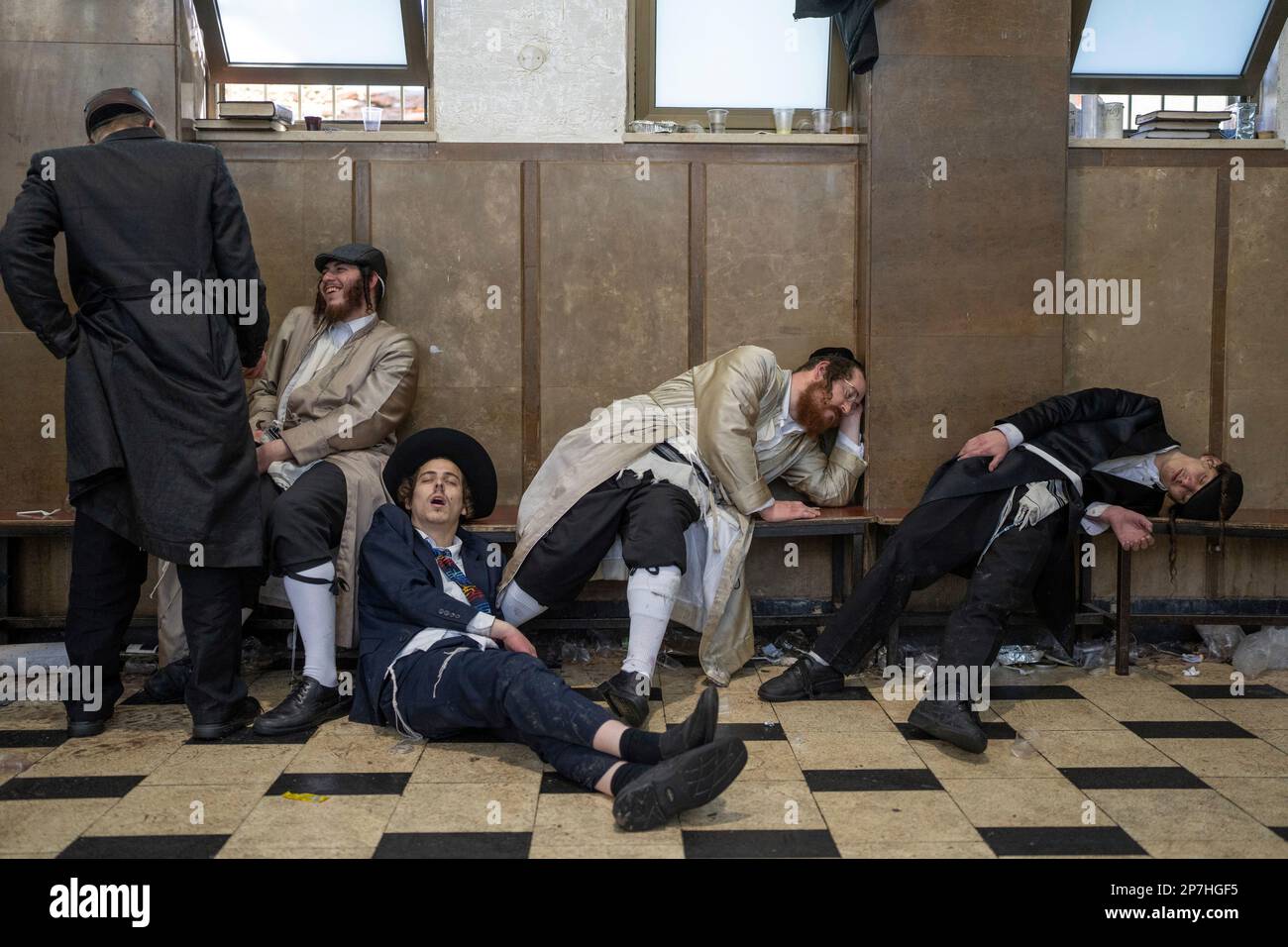 Ultra-orthodox Jewish men rest after getting drunk during celebrations of the Jewish holiday of Purim in Mea Shearim ultra-Orthodox neighborhood in Jerusalem, Wednesday, March 8, 2023. The Jewish holiday of Purim celebrates the Jews' salvation from genocide in ancient Persia, as recounted in the Scroll of Esther. (AP Photo/Ohad Zwigenberg) Stockfoto