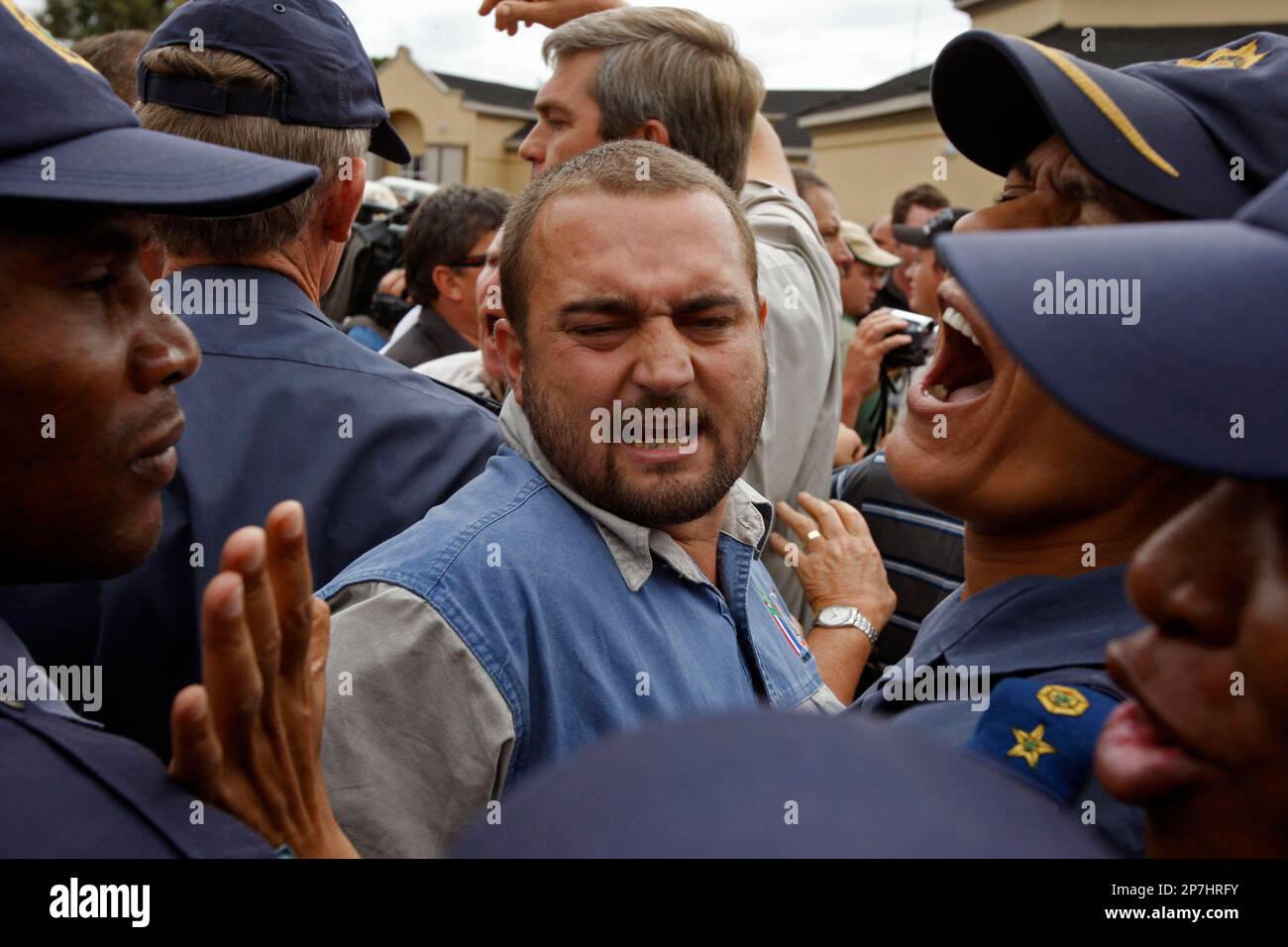 A supporter of slain white supremacist leader Eugene Terreblanche reacts as police try to calm people outside the court in Ventersdorp, South Africa, Tuesday, April 6, 2010. Whites and blacks faced off angrily in song Tuesday in front of a heavily guarded South African courthouse before the first hearing of a teenager and another farm worker who have allegedly confessed to killing a white supremacist leader. (AP Photo/Schalk van Zuydam) Stockfoto