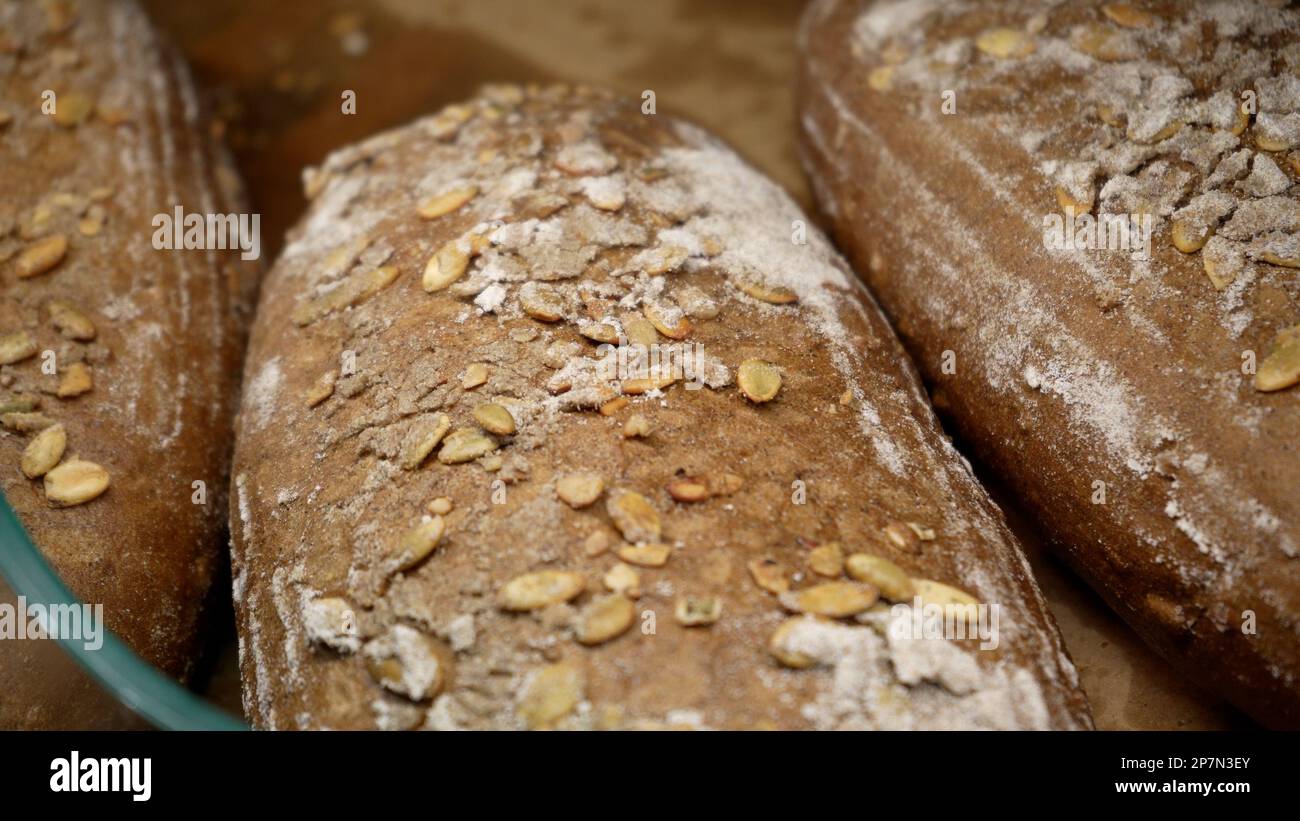 Brotlaibe von Roggenbrot liegen auf dem Holzbakerregal. Nahaufnahme. Einkaufen im Supermarkt. Konzept des Verkaufs von Lebensmitteln Stockfoto