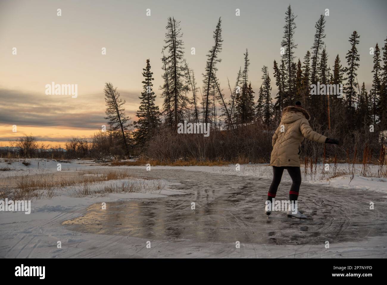 Schlittschuhläuferin auf dem gefrorenen See im wilden und isolierten Yukon Territory im Norden Kanadas. Aktiv, Aktivität, außerhalb von Kanada. Stockfoto