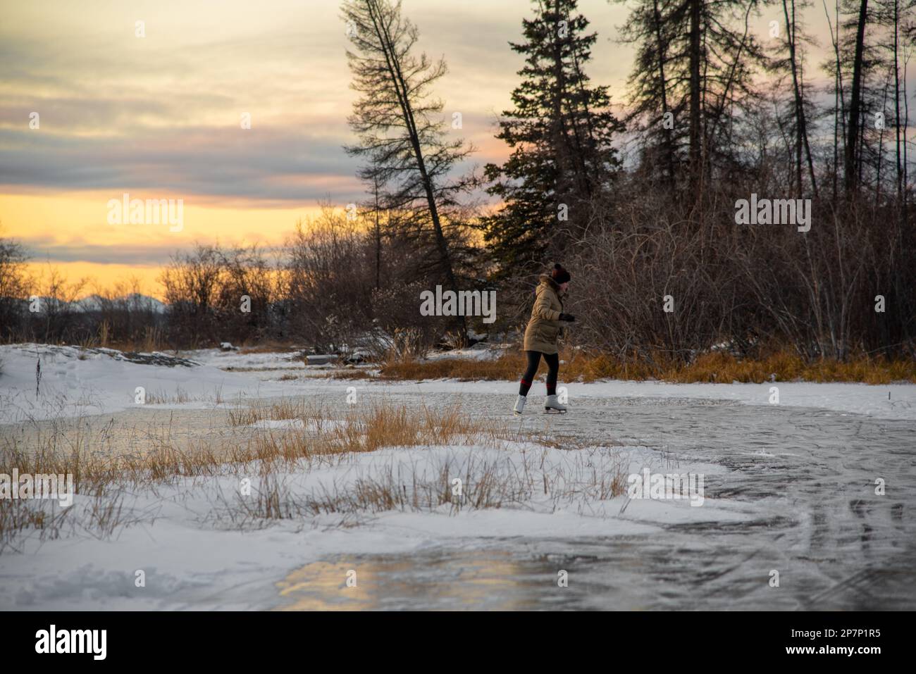 Schlittschuhläuferin auf dem gefrorenen See im wilden und isolierten Yukon Territory im Norden Kanadas. Aktiv, Aktivität, außerhalb von Kanada. Stockfoto