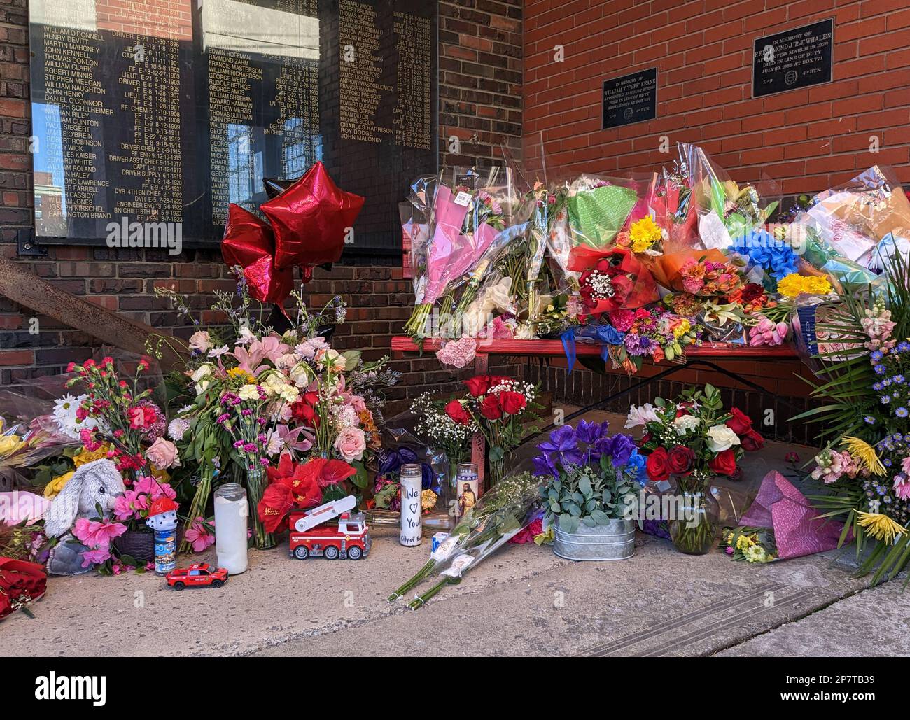 Blumen und andere Gegenstände, die nach dem Tod eines Feuerwehrmanns in der Innenstadt von Buffalo, New York, an einer Gedenkstätte vor einer Feuerwache zurückgelassen wurden. Stockfoto