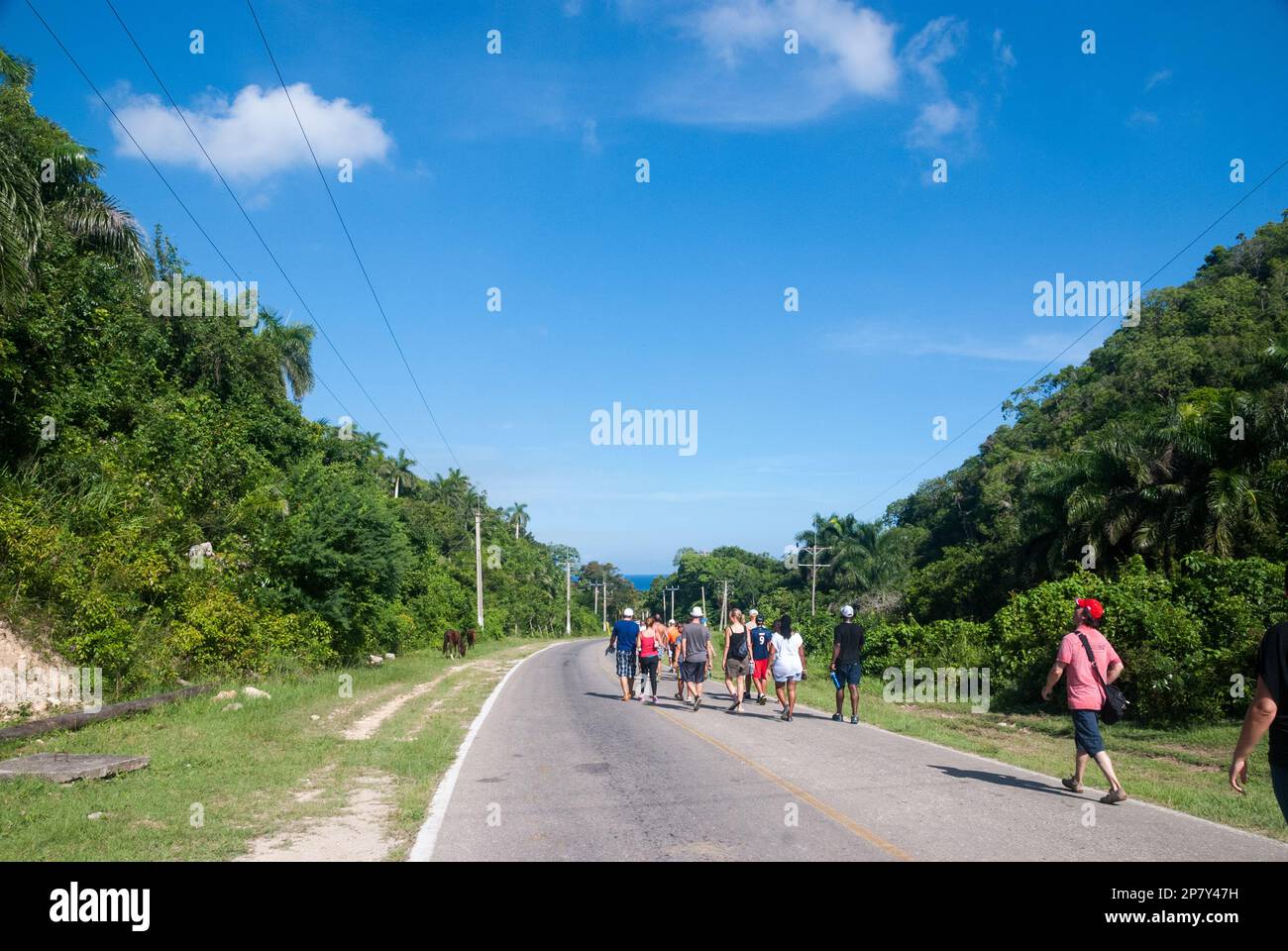 Touristen gehen entlang einer kubanischen Landstraße, um nach einer Wanderung in den Hügeln von Jibacoa in der Nähe von Varadero Cuba zu ihrem Resort zurückzukehren Stockfoto