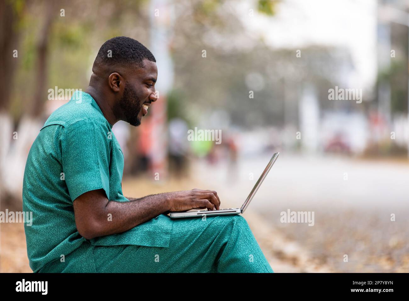 Ein junger afrikanischer Geschäftsmann mit einem Laptop im Freien spricht aus der Ferne mit Kunden, unterrichtet Kunden über Cyber-Sicherheit. Stockfoto