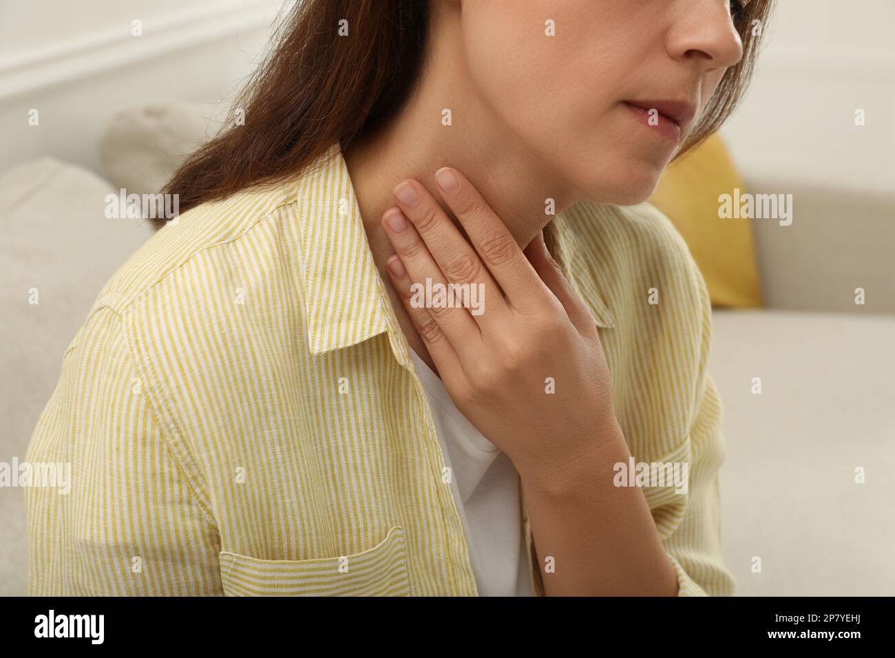 Reife Frau, die sich in geschlossenen Räumen einer Schilddrüsen-Selbstuntersuchung unterzieht, Nahaufnahme Stockfoto
