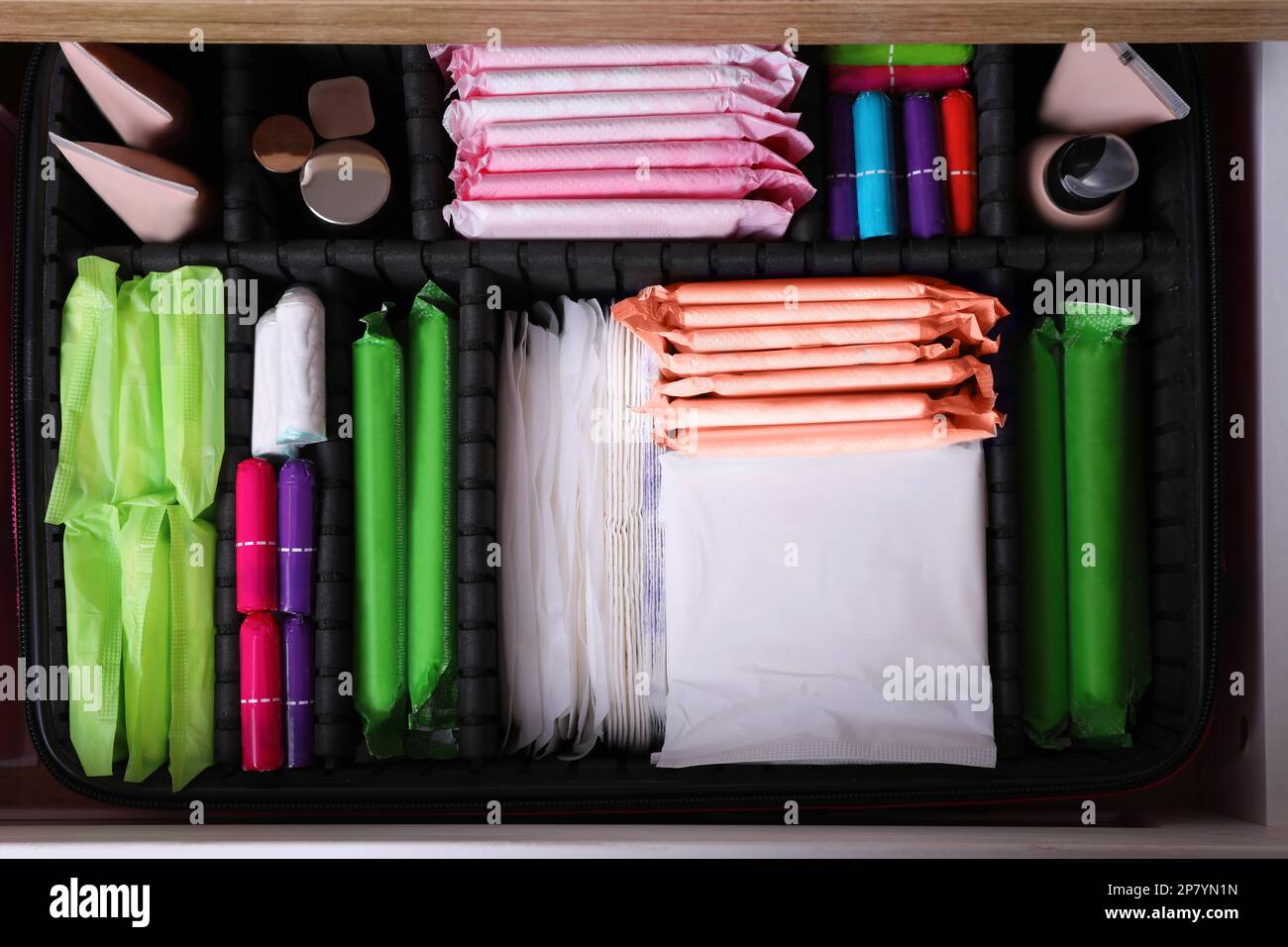 Offene Schublade mit Menstruationseinlagen, Tampons, Make-up- und Hautpflegeprodukten, Draufsicht Stockfoto