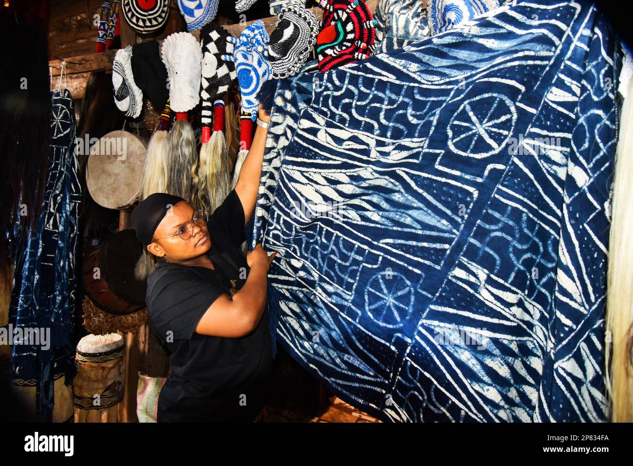 Yaounde, Kamerun. 3. März 2023. Ein Händler arrangiert Ndop-Produkte auf einem Markt in Bafoussam, Kamerun, 3. März 2023. In Kamerun waren Kunsthandwerk wie Nähen, Steppnähen, Stickereien und Stricken schon immer ein Ventil für Frauen, um ihre Kreativität zu nutzen. Ndop-Material wurde ursprünglich von Frauen hergestellt und war ein wichtiges Symbol für sozialen Status und kulturelles Erbe, aber heute - auf eine andere Weise - verbessert es das Leben von Frauen.ZU "Feature: Ndop Fabric verwandelt Frauen in Kleinstunternehmer in Kamerun" zu KOMMEN Kredit: Kepseu/Xinhua/Alamy Live News Stockfoto
