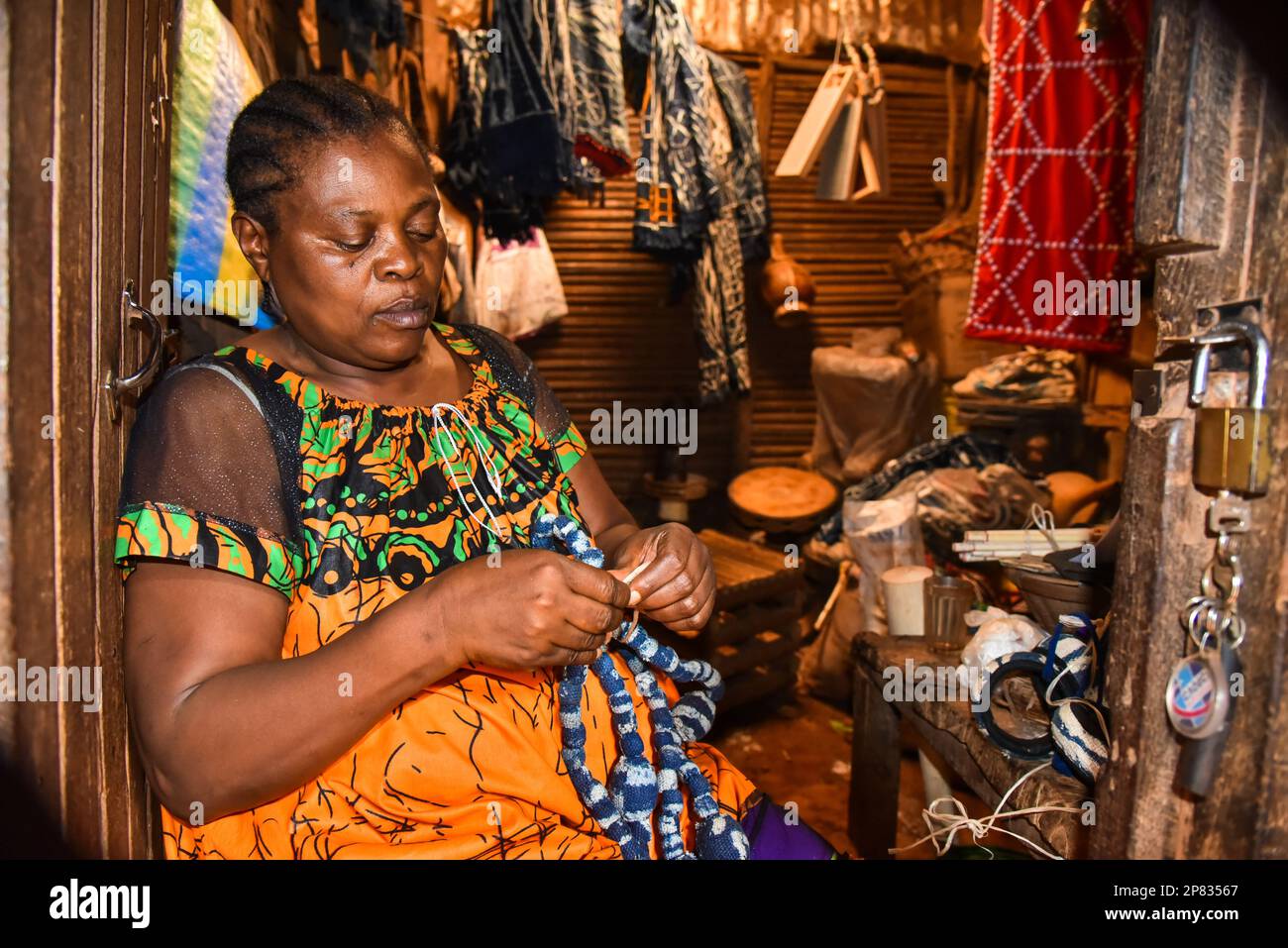 Yaounde, Kamerun. 3. März 2023. Ein Verkäufer arrangiert Halsketten, die mit Ndop auf einem Marktplatz in Bafoussam, Kamerun, am 3. März 2023 hergestellt wurden. In Kamerun waren Kunsthandwerk wie Nähen, Steppnähen, Stickereien und Stricken schon immer ein Ventil für Frauen, um ihre Kreativität zu nutzen. Ndop-Material wurde ursprünglich von Frauen hergestellt und war ein wichtiges Symbol für sozialen Status und kulturelles Erbe, aber heute - auf eine andere Weise - verbessert es das Leben von Frauen.ZU "Feature: Ndop Fabric verwandelt Frauen in Kleinstunternehmer in Kamerun" zu KOMMEN Kredit: Kepseu/Xinhua/Alamy Live News Stockfoto