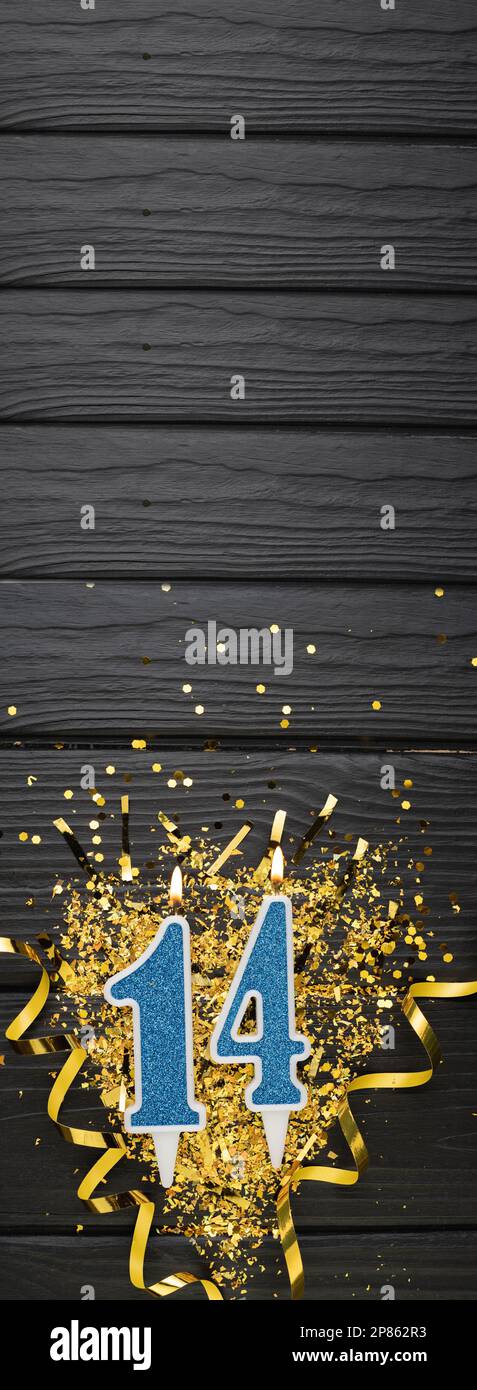 Blaue Festkerze Nummer 14 und goldene Konfetti auf dunklem Holzhintergrund. 14. Geburtstagskarte. Jubiläums- und Geburtstags Vertikales Banner. Stockfoto