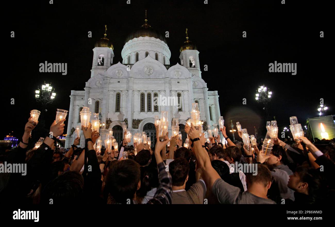 People hold candles as they attend a candle-lit vigil in memory of the victims of the August 2008 war involving Russia and Georgia, outside the Christ the Savior Cathedral in Moscow, late Friday, Aug. 7, 2009. Kremlin youth groups gathered late Friday near the Moscow's central cathedral in a show of support for the breakaway Georgian province of South Ossetia. (AP Photo/Alexander Zemlianichenko Jr.) Stockfoto