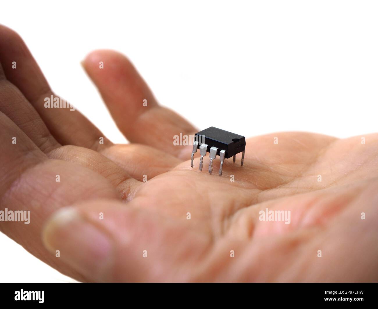 Eine Hand mit einem 8-Pin-Chip. Isoliertes elektronisches Bauteil, integrierter Schaltkreis. Halbleitertechnologie. Stockfoto