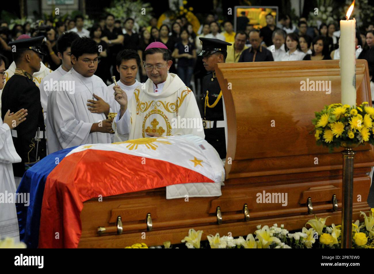 A Filipino priest blesses the casket of former Philippines president Corazon Aquino during her wake in Manila, Saturday Aug. 1, 2009. "Cory" Aquino, whose "People Power" revolution toppled dictator Ferdinand Marcos, died Saturday after a battle with colon cancer. Military honor guards carried former President Corazon Aquino's flag-draped casket to a school gym Saturday for public viewing, as Filipinos mourned the beloved democracy icon who swept away a dictator and fought off seven coup attempts.(AP Photo/Jay Directo, pool) Stockfoto