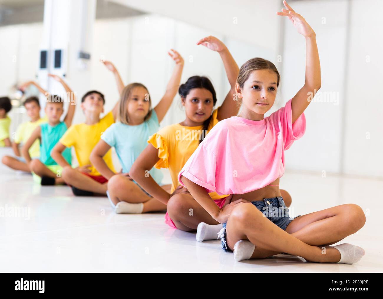 Gruppe emotionaler Kinder, die im Tanzstudio Yoga machen Stockfoto