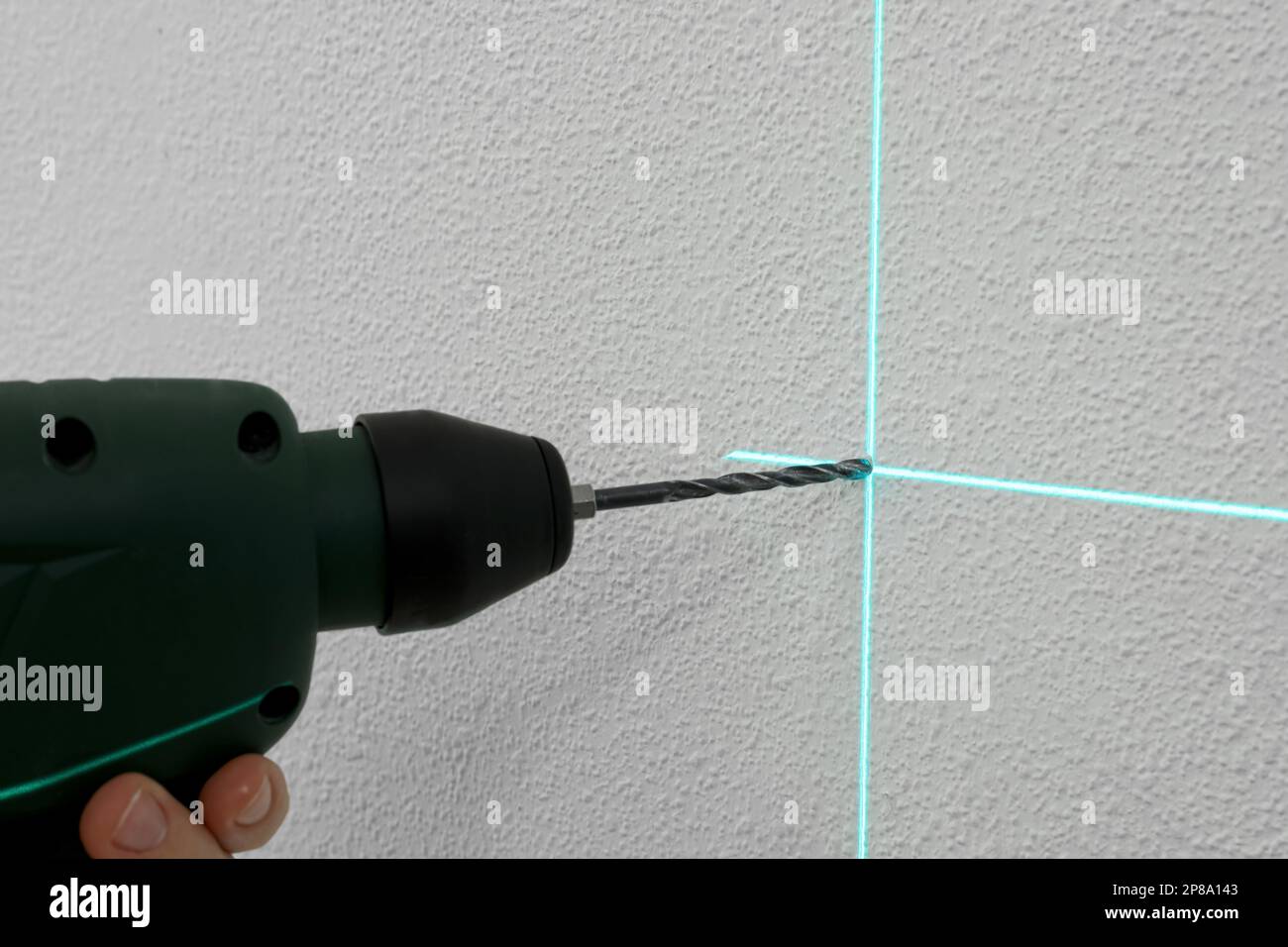 Verwendung von Kreuzlinien-Laser-Nivelliergeräten für genaue Messungen und Bohren von Löchern in weißen Wänden, Nahaufnahme Stockfoto