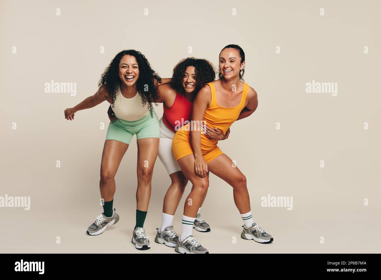 Eine Gruppe junger Sportlerinnen, die lachen und Spaß in Fitnesskleidung haben und ihre Liebe zu Sport und Bewegung feiern. Fröhliche junge Sportlerinnen dem Stockfoto