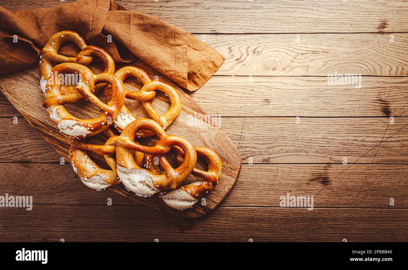 Frisch gebackene hausgemachte deutsche Brezel mit Meersalz auf einem Holztisch. Klassischer Biersnack, gebackenes Gebäck. Stockfoto