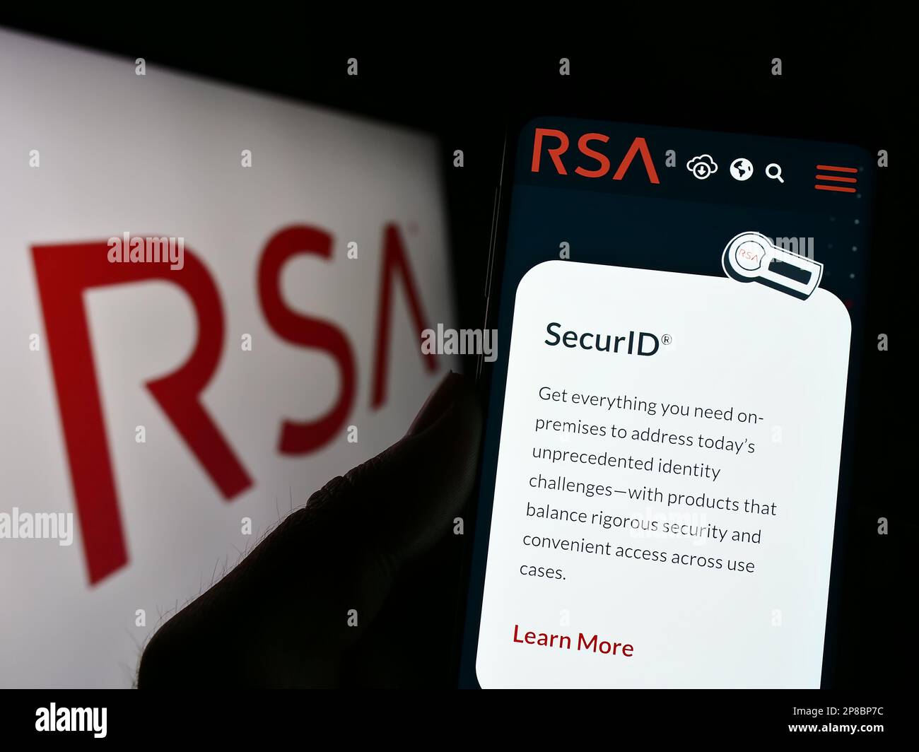 Person, die ein Mobiltelefon mit einer Webseite des US-Unternehmens RSA Security LLC auf dem Bildschirm vor dem Unternehmenslogo hält. Konzentrieren Sie sich auf die Mitte des Telefondisplays. Stockfoto