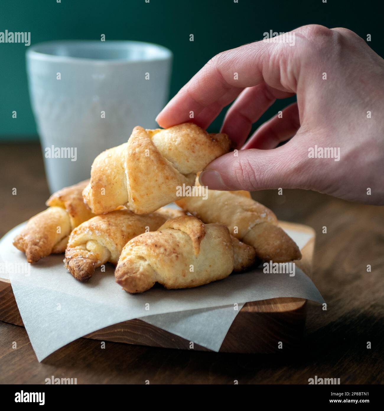 Miniatur-Halbmond-Gebäck in der Hand, selektiver Fokus. Mini-Croissants oder Rugelache. Ein Haufen köstlicher goldbrauner Kekse Stockfoto
