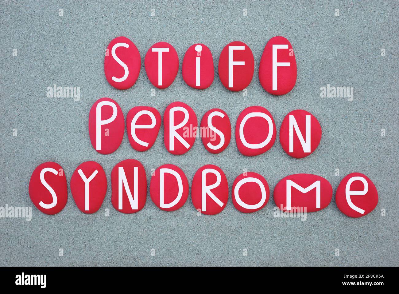 Steife Person-Syndrom, sps, seltene, progressive neurologische Störung, Text mit rot gemalten Steinbuchstaben über grünem Sand Stockfoto