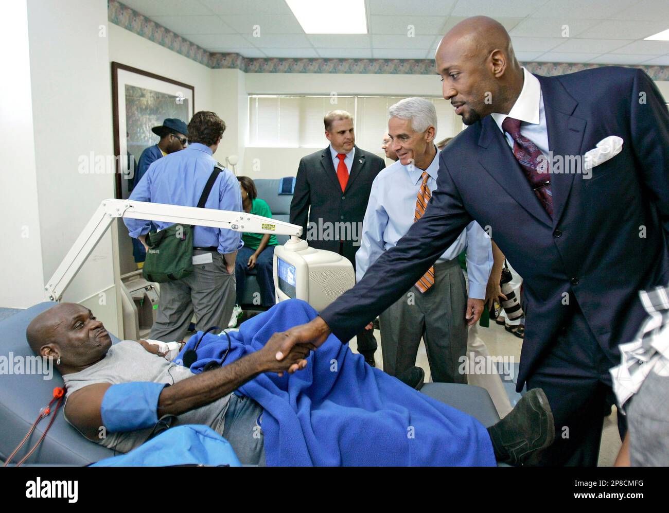 Former Miami Heat player Alonzo Mourning, right, shakes hands with