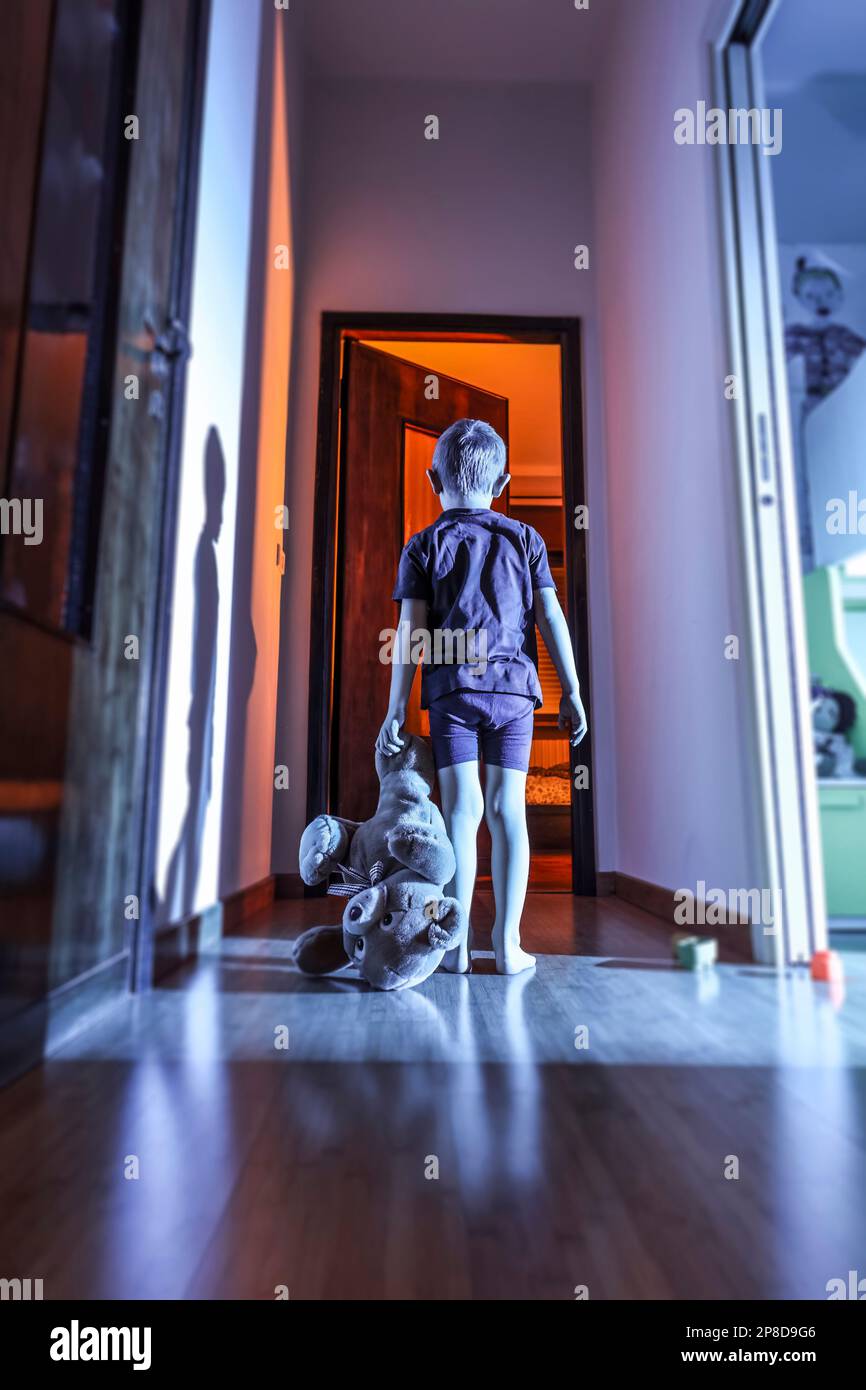 Kind mit Teddybär in häuslicher Umgebung, nachts und geheimnisvoller Atmosphäre Stockfoto