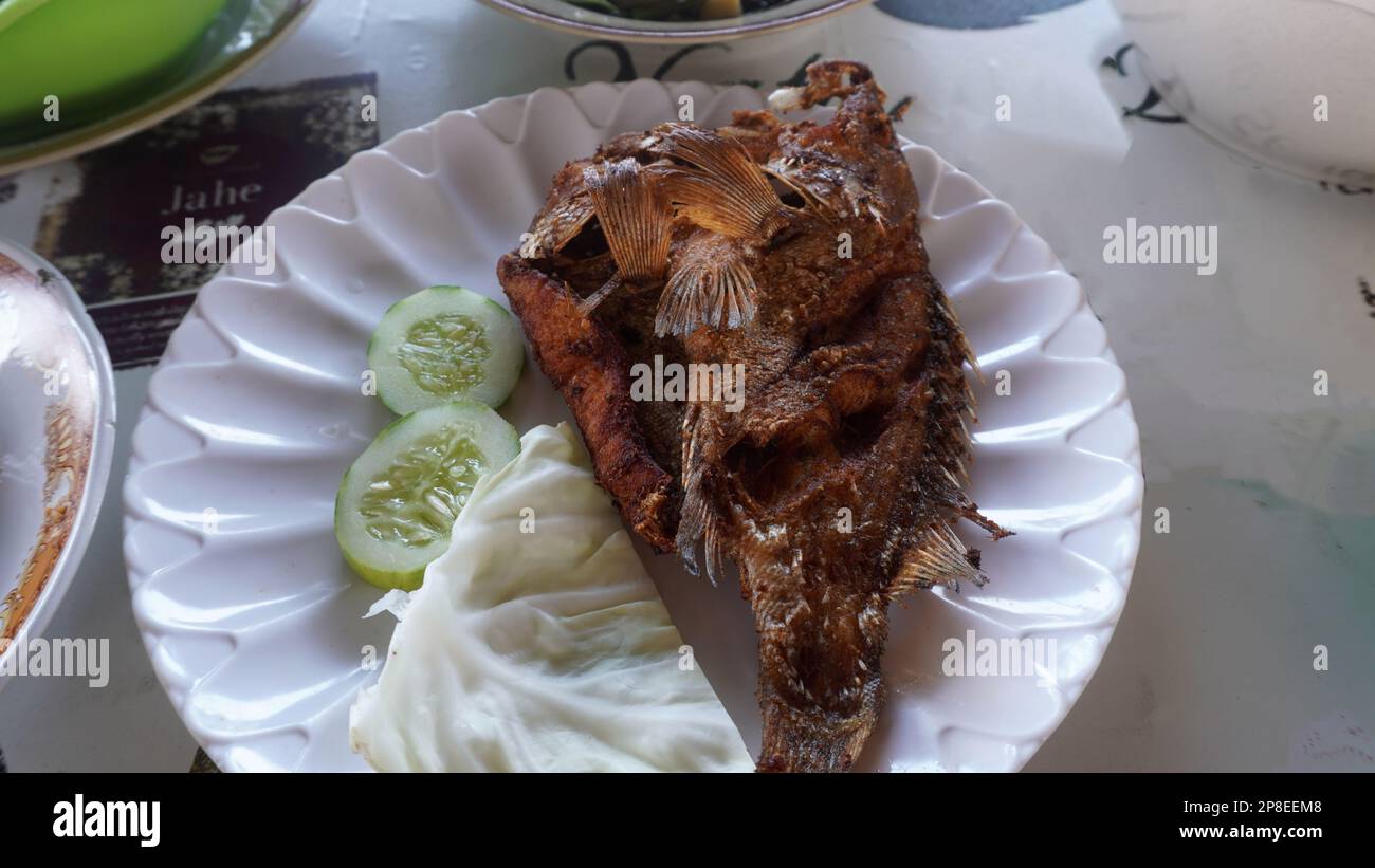 Gebratener Fisch mit einer Scheibe Gurke und Weißkohl-Gemüse Stockfoto