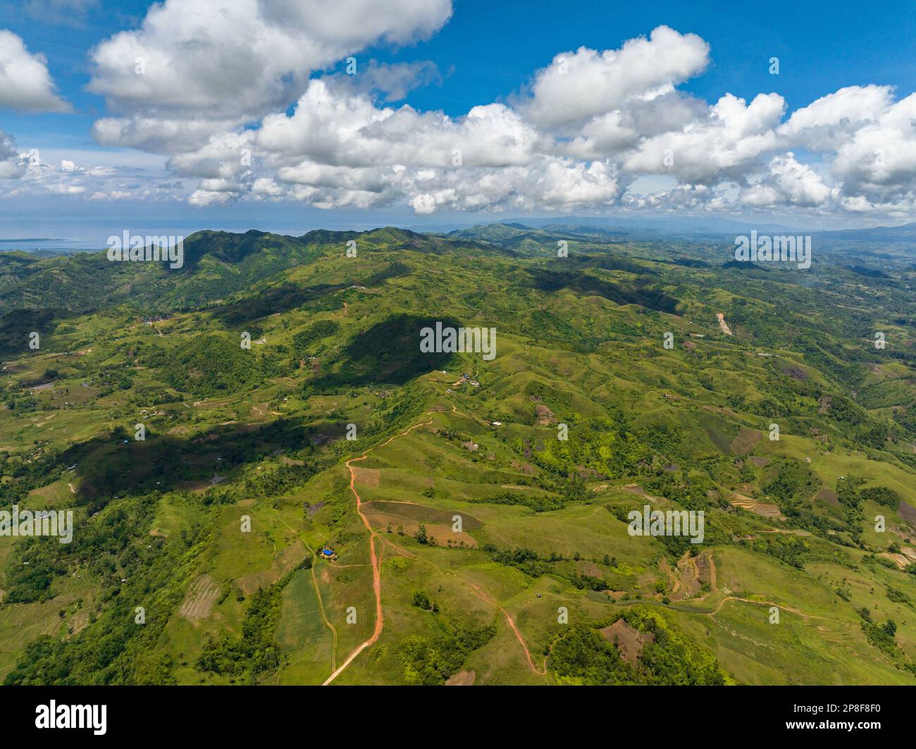 Luftaufnahme von Ackerland vor blauem Himmel und Wolken in einem Gebirgsgebiet. Negros, Philippinen Stockfoto