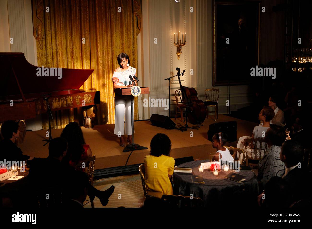 First lady Michelle Obama speaks during "an evening of poetry, music and the spoken word" in the East Room of the White House in Washington, Tuesday, May 12, 2009. At table in foreground are their daughters Malia, left, and Sasha Obama, and President Barack Obama is seen bottom right. (AP Photo/Gerald Herbert) Stockfoto