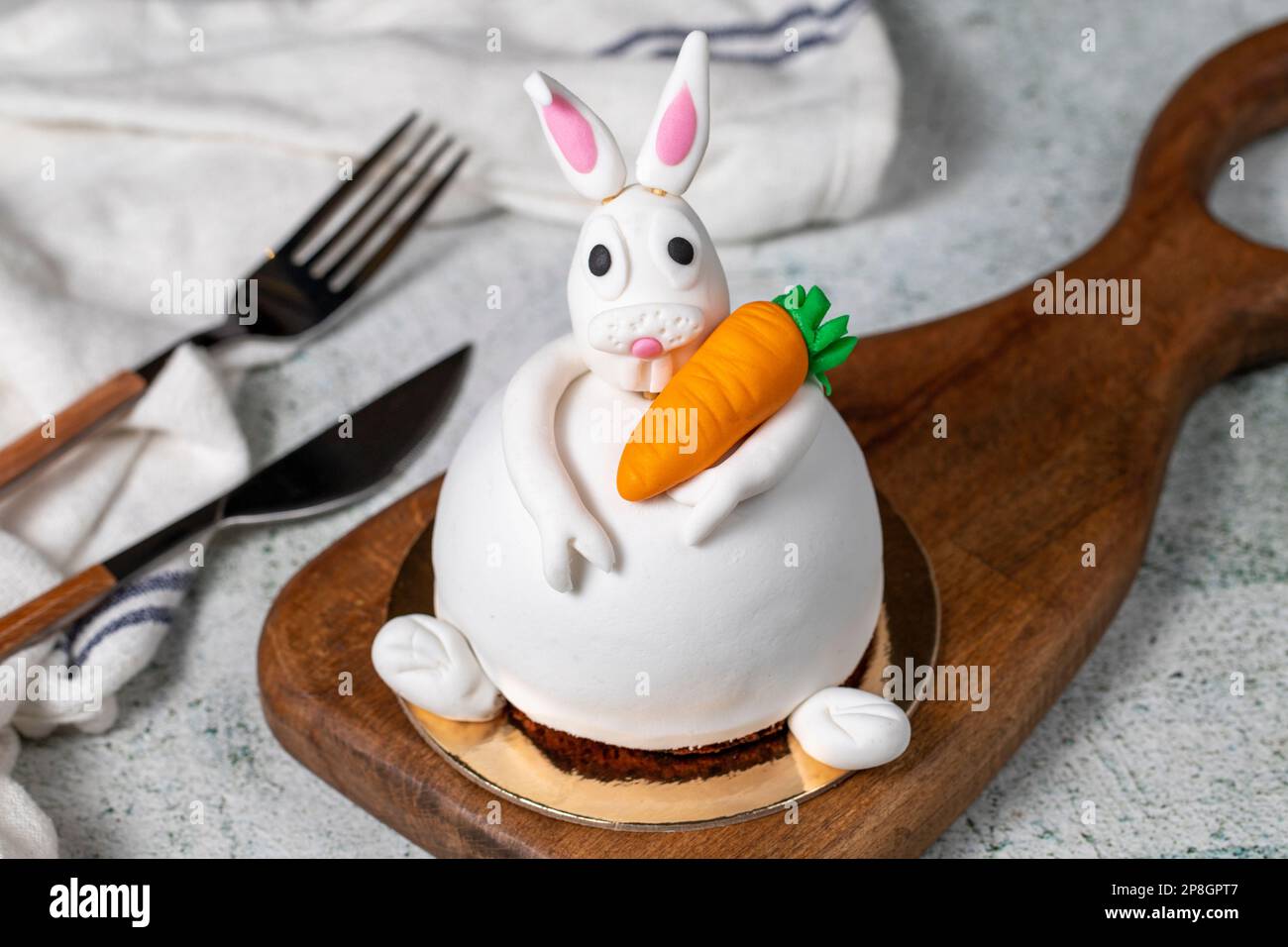 Speziell entworfener Kuchen in Hasenform. Kuchen auf grauem Holztisch und Osterhase Stockfoto